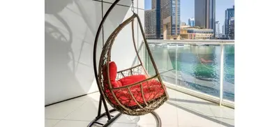 a red chair sitting in a room with a window at Luxurious 4-Bedroom Duplex VILLA Apartment near JBR in Dubai