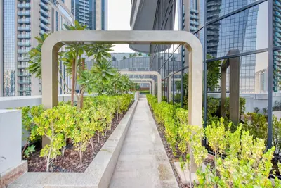 a corridor of plants on a building with tall buildings at RH- Downtown Delight, Chic 01BR near Dubai Mall & Burj Khalifa, RP Heights in Dubai