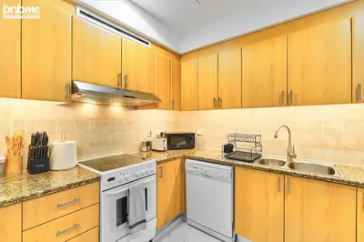 a kitchen with wooden cabinets and white appliances at bnbme - Dubai Marina 2BR Apt w Private Jacuzzi Pool Gym Near JBR Beach & Marina Walk in Dubai