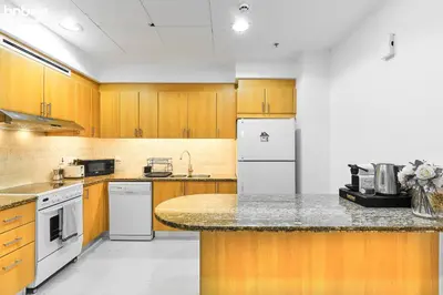 a kitchen with wooden cabinets and a white refrigerator at bnbme - Dubai Marina 2BR Apt w Private Jacuzzi Pool Gym Near JBR Beach & Marina Walk in Dubai
