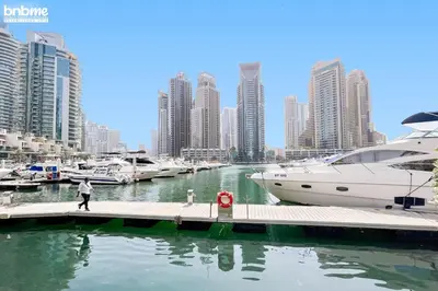 a man walking on a dock next to a marina with boats at bnbme - Dubai Marina 2BR Apt w Private Jacuzzi Pool Gym Near JBR Beach & Marina Walk in Dubai