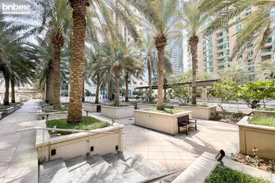 a courtyard with palm trees in a building at bnbme - Dubai Marina 2BR Apt w Private Jacuzzi Pool Gym Near JBR Beach & Marina Walk in Dubai