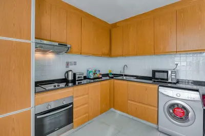a kitchen with wooden cabinets and a washing machine at Grand Heights Dubai Hotel Apartments in Dubai