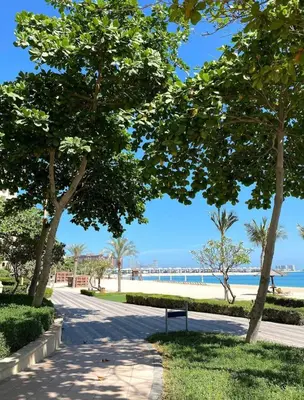 a park with trees and the beach in the background at Lux 2BR in Al Khushkar Shoreline -Palm Jumeirah in Dubai