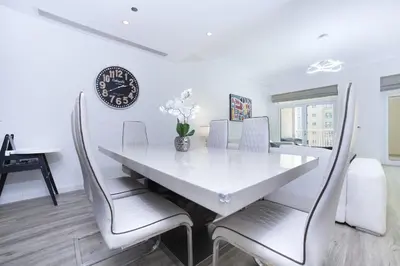 a dining room table with chairs and a clock on the wall at Lux 2BR in Al Khushkar Shoreline -Palm Jumeirah in Dubai