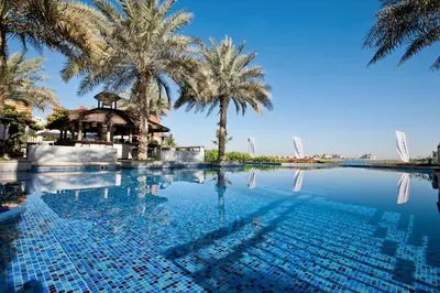 a swimming pool with palm trees in the background at Lux 2BR in Al Khushkar Shoreline -Palm Jumeirah in Dubai