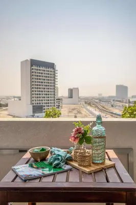 a table with flowers on a balcony with a view of a city at Frank Porter - Azizi Aura in Dubai