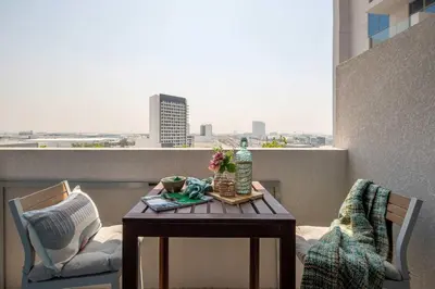 a table on a balcony with a view of a city at Frank Porter - Azizi Aura in Dubai