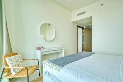 a bedroom with a bed and a chair and a mirror at Boho-Chic Cosy 1BR, minutes to Burj Khalifa in Dubai