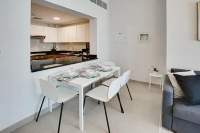 a white dining table and chairs in a living room at 1BD apt in Sparkle Tower by Swarovsky big capacity in Dubai
