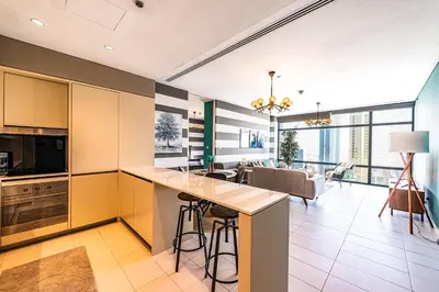 an open kitchen with yellow cabinets and a living room at Index Tower by Radiance Vacation Stays 43rd Floor in Dubai