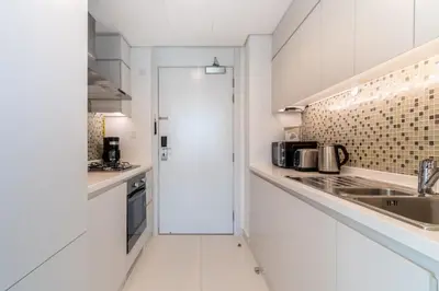 a white kitchen with white cabinets and a sink at The Smart Concierge - The Vogue in Dubai
