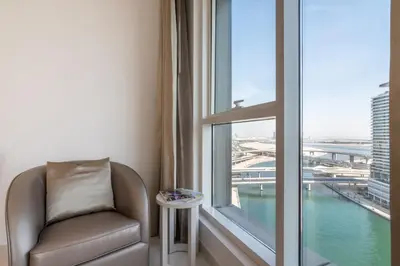 a chair in a room with a large window at The Smart Concierge - The Vogue in Dubai