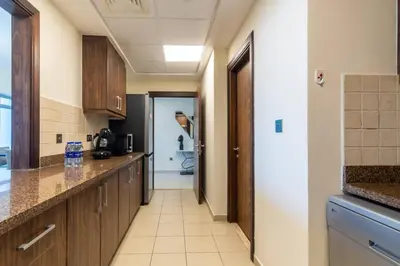 a kitchen with wooden cabinets and a hallway with a toilet at Scenic 2 Bedroom Apartment - Downtown Business Bay in Dubai