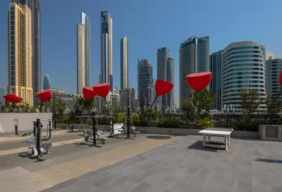 a park with red umbrellas in front of a city at Bespoke Holiday Homes - Mag 318 Downtown Dubai in Dubai