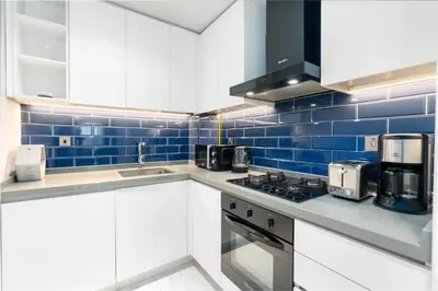 a kitchen with white cabinets and blue tiles at Bespoke Holiday Homes - Mag 318 Downtown Dubai in Dubai