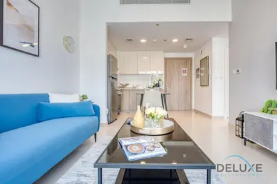 a living room with a blue couch and a table at Chic 1BR in Town Square UNA Dubailand by Deluxe Holiday Homes in Dubai