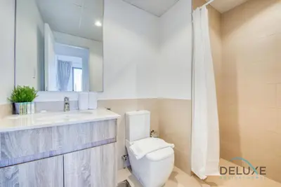 a bathroom with a toilet and a sink and a mirror at Chic 1BR in Town Square UNA Dubailand by Deluxe Holiday Homes in Dubai