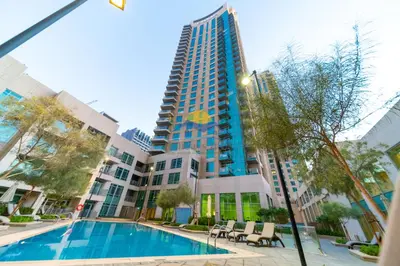 a large apartment complex with a swimming pool and a tall building at Holidays R Us canal view in Dubai