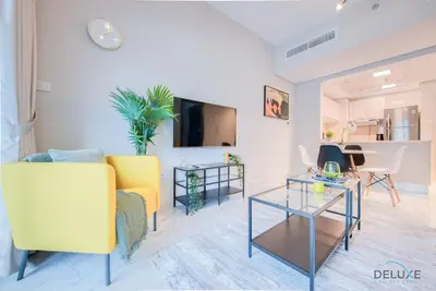 a living room with a yellow couch and a table at Snug 1BR at MAG 520 Dubai South by Deluxe Holiday Homes in Dubai