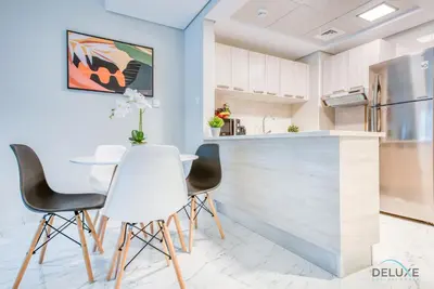 a kitchen with white chairs and a table at Snug 1BR at MAG 520 Dubai South by Deluxe Holiday Homes in Dubai