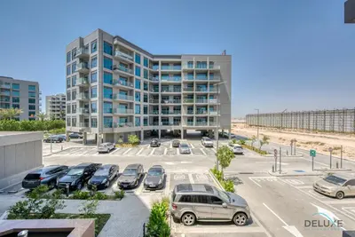 a parking lot with cars parked in front of a building at Snug 1BR at MAG 520 Dubai South by Deluxe Holiday Homes in Dubai