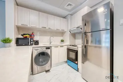 a kitchen with a washing machine and a refrigerator at Snug 1BR at MAG 520 Dubai South by Deluxe Holiday Homes in Dubai