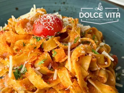 a plate of pasta with a tomato on top at Asma Hotel Al Barsha in Dubai