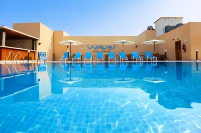 a swimming pool with blue chairs and umbrellas at Asma Hotel Al Barsha in Dubai