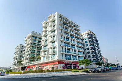 a tall white building with cars parked in front of it at Live Modern Live Luxury - Dubai Studio City in Dubai
