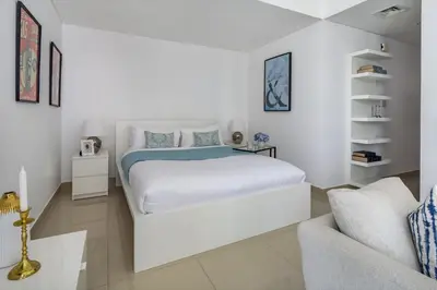 a white bedroom with a bed and a couch at Frank Porter - The Medalist in Dubai