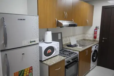 a small kitchen with a refrigerator and a sink at Comfortable Apartments and Studios for Rent in Dubai in Dubai