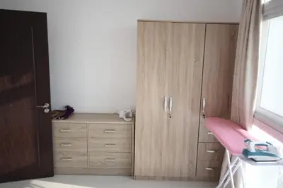 a bedroom with a wooden cabinet and a pink desk at Comfortable Apartments and Studios for Rent in Dubai in Dubai