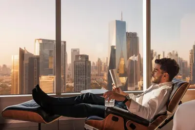 a man sitting in an office chair reading a book at Jumeirah Emirates Towers Dubai in Dubai
