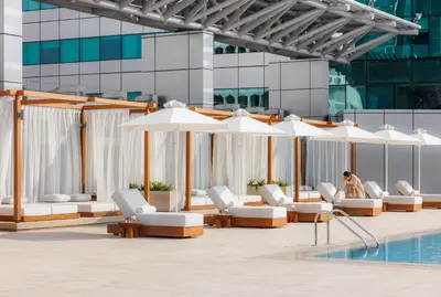 a pool with white lounge chairs and umbrellas at Jumeirah Living World Trade Centre Dubai in Dubai