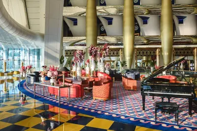 a lobby with a grand piano and red chairs at Jumeirah Burj Al Arab Dubai in Dubai