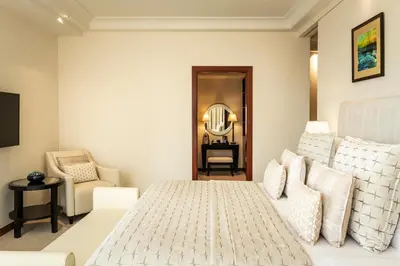 a bedroom with a bed and a chair and a mirror at Grosvenor House, a Luxury Collection Hotel, Dubai in Dubai