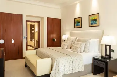 a white bedroom with a bed and a chair at Grosvenor House, a Luxury Collection Hotel, Dubai in Dubai