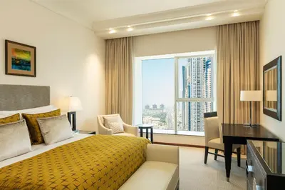 a hotel room with a bed and a desk and a window at Grosvenor House, a Luxury Collection Hotel, Dubai in Dubai