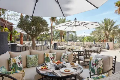 an outdoor patio with tables and chairs and umbrellas at Jumeirah Al Qasr Dubai in Dubai