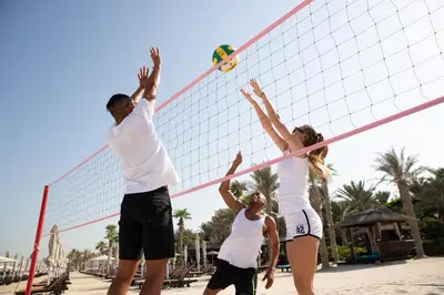 a group of people playing volleyball on the beach at Jumeirah Dar Al Masyaf Dubai in Dubai