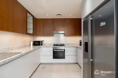 a kitchen with white cabinets and a refrigerator at Dream Inn Apartments- Boulevard Heights in Dubai