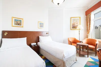 a hotel room with two beds and a chair at Royal Club By RVHR, Palm Jumeirah in Dubai