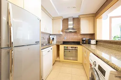 a kitchen with a refrigerator and a dishwasher at Royal Club By RVHR, Palm Jumeirah in Dubai