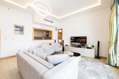a living room with a white couch and a tv at Royal Club By RVHR, Palm Jumeirah in Dubai