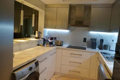 a kitchen with white cabinets and a washer in it at Royal Club By RVHR, Palm Jumeirah in Dubai