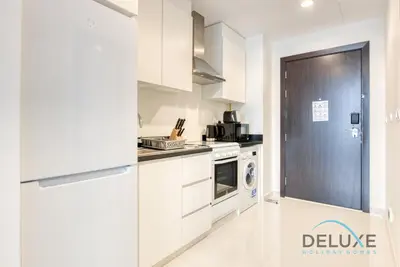 a kitchen with white cabinets and a washer and dryer at Calm Studio in Damac Celestia A Dubai South by Deluxe Holiday Homes in Dubai