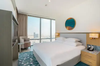 a bedroom with a white bed and a large window at The First Collection Dubai Jumeirah Village Circle, a Tribute Portfolio Hotel in Dubai