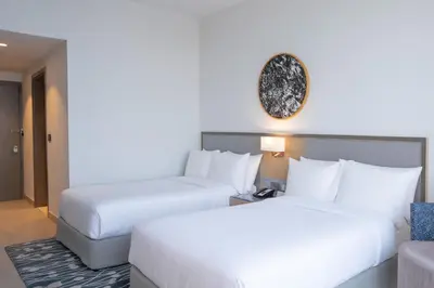 a hotel room with two beds and a couch at The First Collection Dubai Jumeirah Village Circle, a Tribute Portfolio Hotel in Dubai