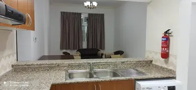 a kitchen with a sink and a living room at Furnished Studio Apartments for rent in Dubai in Dubai